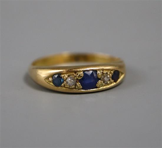 An early 20th century 18ct gold, three stone sapphire and two stone diamond ring, size N.